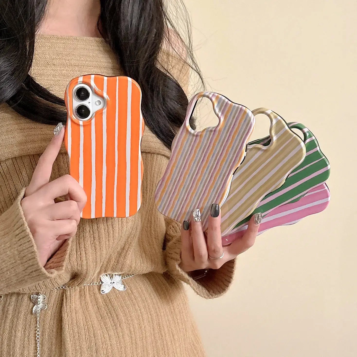 Person holding various colors of iPhone 2-in-1 striped phone case in their hands.