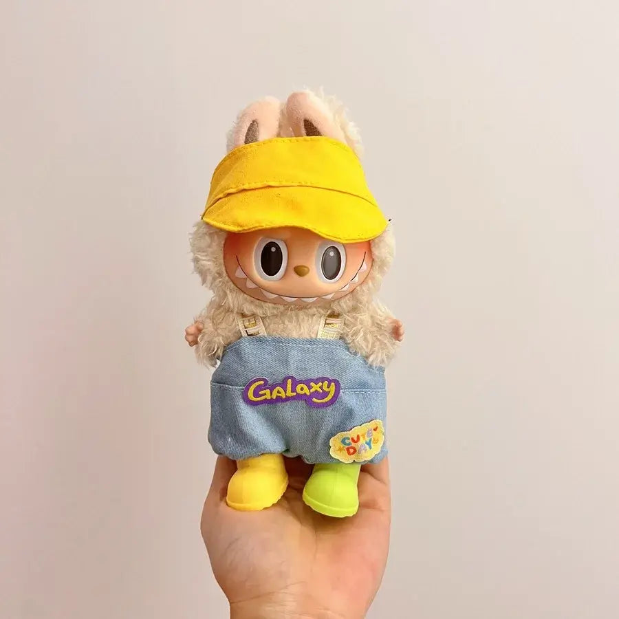 Labubu doll clothes 17cm on a cute doll wearing a yellow cap and blue overalls with bunny ears.