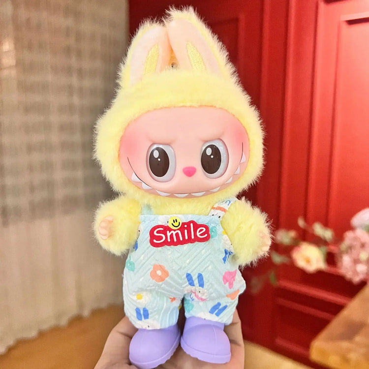 Labubu doll clothes 17cm on a cute bunny doll wearing a yellow hat and blue overalls with smile logo.
