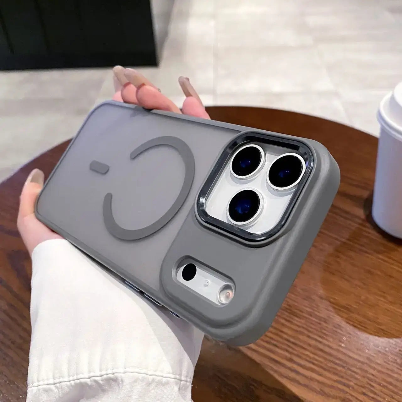 Magneettinen puhelinkuori iPhone in gray held in hand, showcasing its stylish and protective design.