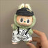 Labubu doll clothes 17cm on a cute green character wearing a black cap and math-themed shorts.