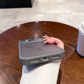 Magneettinen Puhelinkuori iPhone shown in hand over wooden table, showcasing sleek design and charging port.