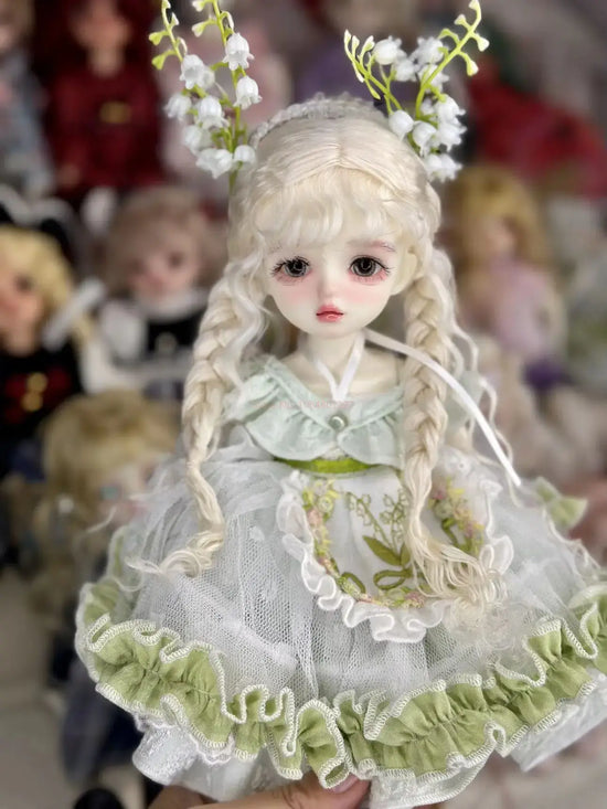 6 niveltä prinsessanukke meikillä in a whimsical dress with floral accents and delicate features.