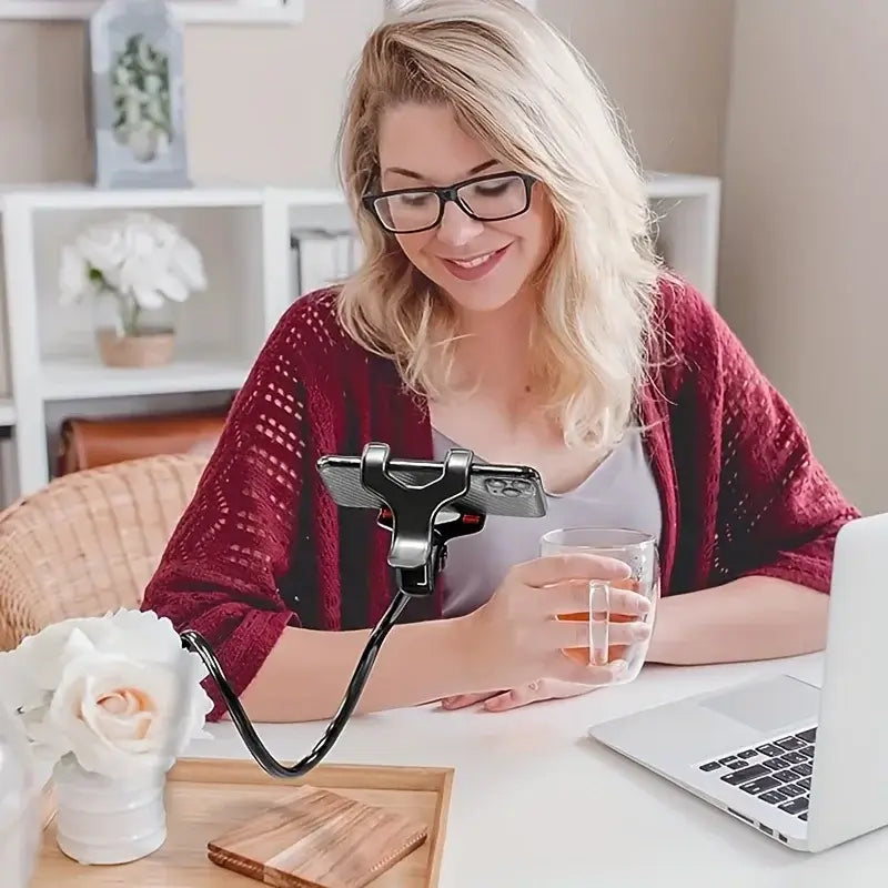 Young woman using joustava puhelinteline pitkällä varrella to hold her phone while enjoying a drink at her desk.