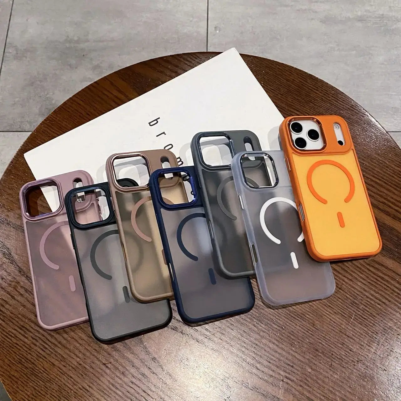 Magneettinen puhelinkuori iPhone cases in various colors displayed on a wooden table.