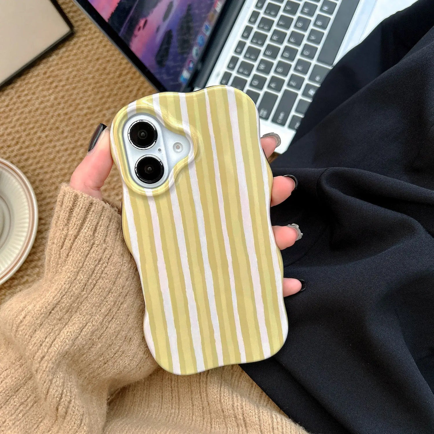 iPhone 2-in-1 striped phone case with a green and white striped design, held in hand near a laptop.