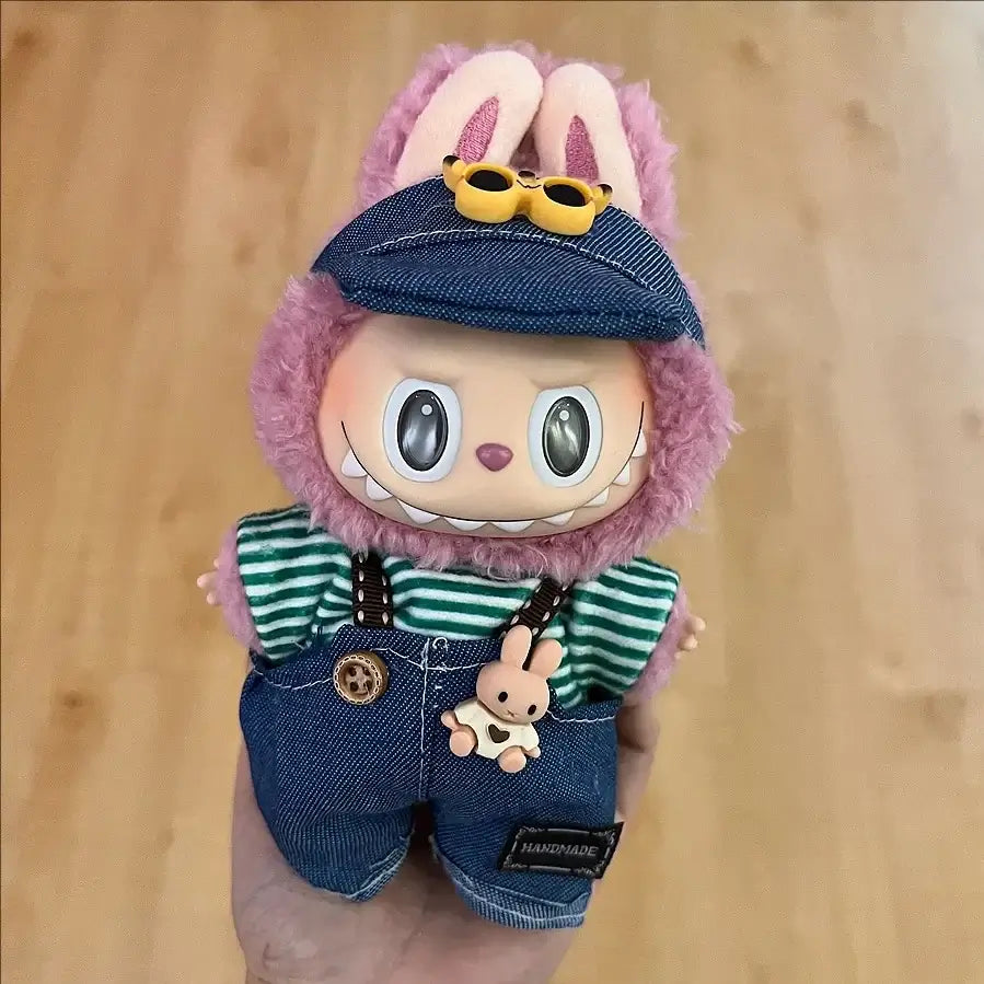 Labubu doll clothes 17cm on a cute doll with a bunny face wearing denim overalls and a green striped shirt.